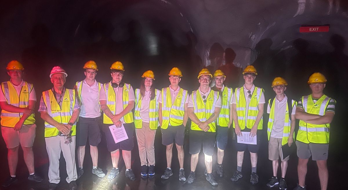 A group of people wearing hard hats and hi-vis vests in an underground structure